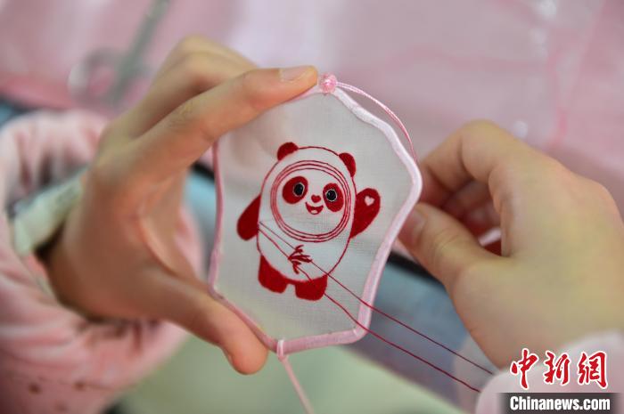 圖為一名小學(xué)生正在繡制2022年北京冬奧會(huì)吉祥物“冰墩墩”形象?！∮髟屏?攝