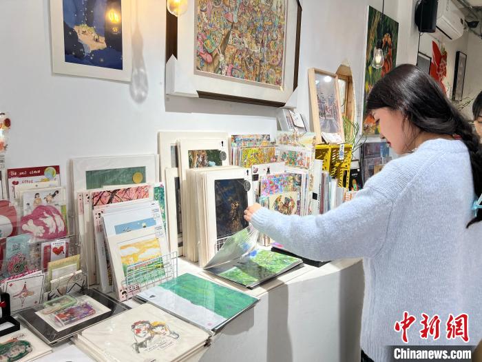 圖為藝術品商店內，顧客挑選插畫作品?！＄婌?攝