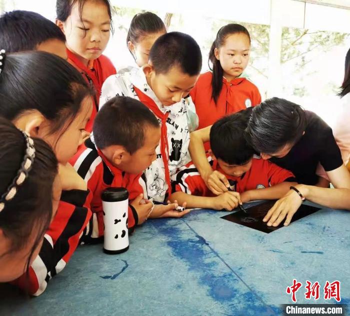 圖為朱增平(右一)教學(xué)生創(chuàng)作鍥金畫(huà)。(資料圖) 受訪者供圖