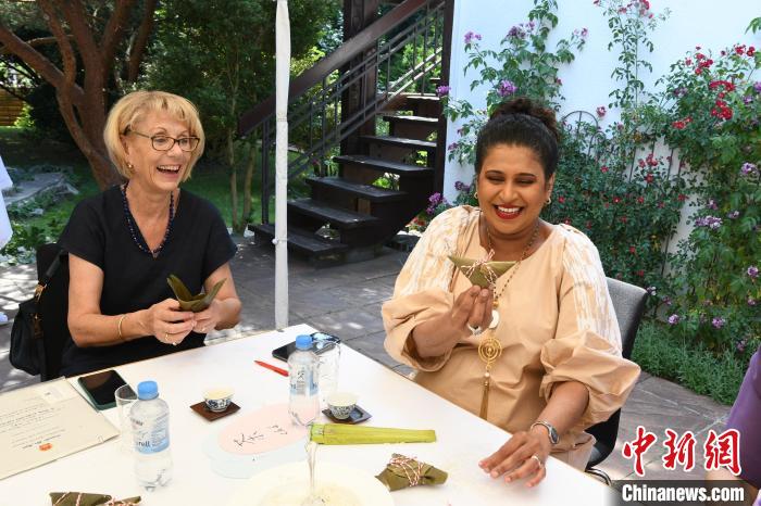 圖為嘉賓展示包粽子成果?！“亓种袊幕行墓﹫D。