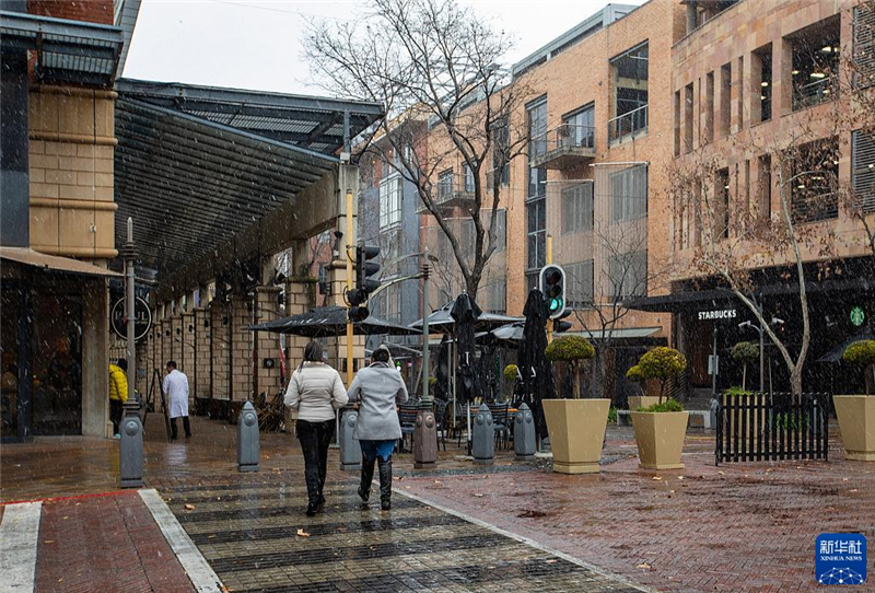 7月10日，在南非約翰內(nèi)斯堡一處商業(yè)區(qū)，人們?cè)谘┲行凶?。新華社記者 張譽(yù)東 攝