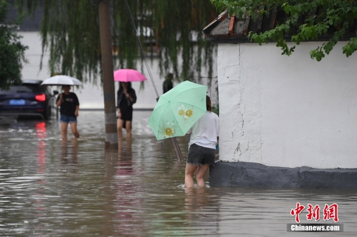 7月31日，市民行走在雨中的北京房山區(qū)瓦窯頭村。北京市氣象臺(tái)當(dāng)日10時(shí)發(fā)布分區(qū)域暴雨紅色預(yù)警信號(hào)。北京市水文總站發(fā)布洪水紅色預(yù)警，預(yù)計(jì)當(dāng)日12時(shí)至14時(shí)，房山區(qū)大石河流域?qū)⒊霈F(xiàn)紅色預(yù)警標(biāo)準(zhǔn)洪水。<a target='_blank' href='/'><p  align=