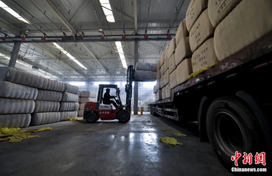 新疆喀什綜合保稅區(qū)，喀什啟路國際貿(mào)易有限公司的倉庫內(nèi)，工人正在裝載從塔吉克斯坦和烏茲別克斯坦進口的棉花。劉新攝