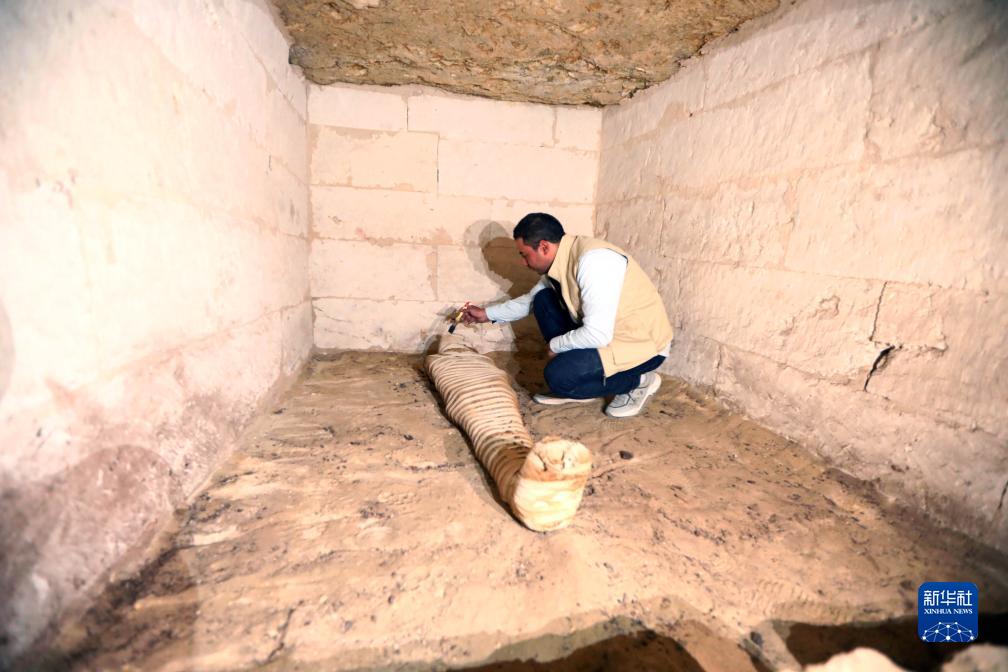 10月15日，在埃及明亞省考古現(xiàn)場(chǎng)，考古人員清理一座石鑿墓中的木乃伊。新華社發(fā)（艾哈邁德·戈馬攝）