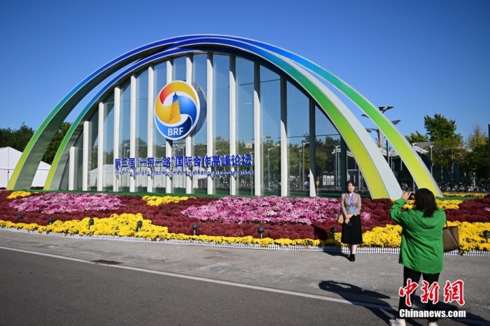 10月15日，北京，工作人員在國家會議中心外的第三屆“一帶一路”國際合作高峰論壇景觀布置前拍照留念。當(dāng)日，位于國家會議中心的第三屆“一帶一路”國際合作高峰論壇新聞中心啟動(dòng)試運(yùn)行。據(jù)悉，第三屆“一帶一路”國際合作高峰論壇將于10月17日至18日在北京舉行。<a target='_blank' href='/'><p  align=