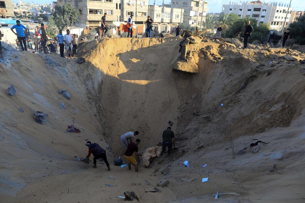 10月16日，在加沙地帶南部城市汗尤尼斯，人們?cè)谠庖陨幸u擊后的建筑廢墟中救援傷者。 新華社發(fā)（亞西爾·庫(kù)迪 攝）