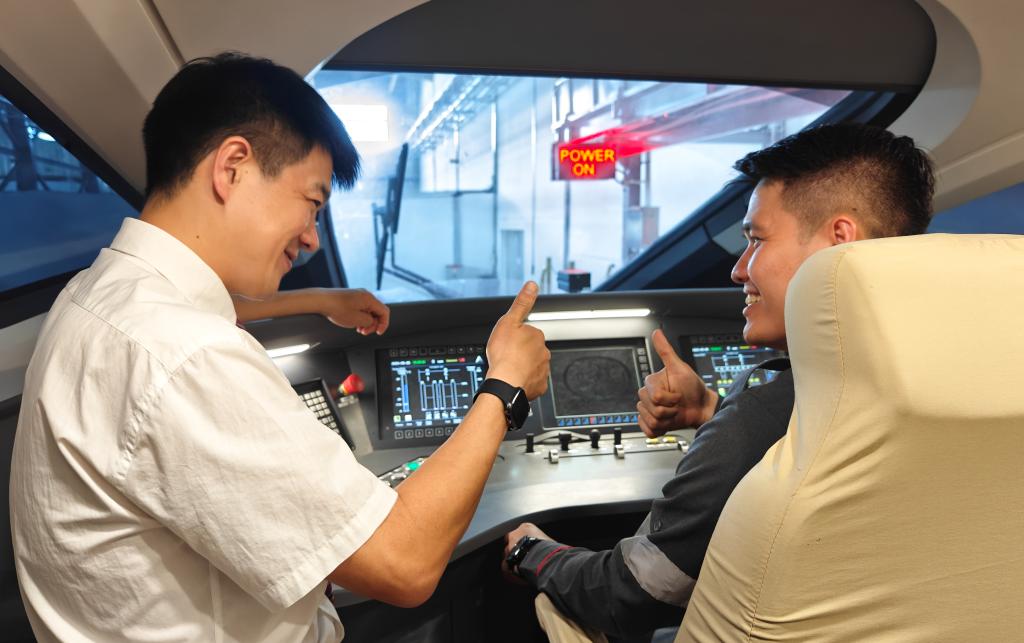 8月25日，在印度尼西亞萬隆的雅萬高鐵德卡魯爾動車所內(nèi)，中國師傅穆振（左）在向印尼火車司機塞蒂亞萬講解動車組出庫前的上電作業(yè)。