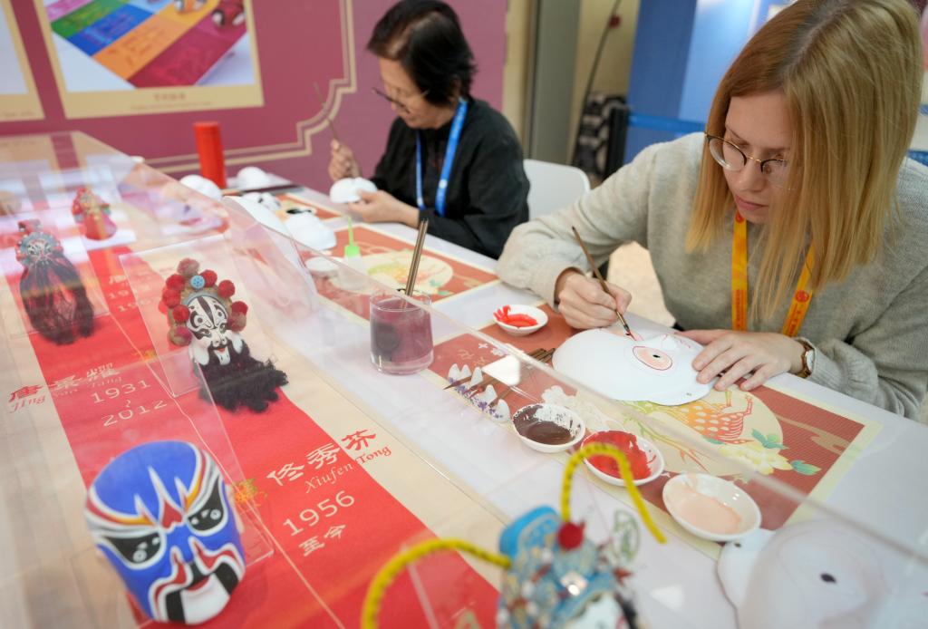 10月16日，在第三屆“一帶一路”國際合作高峰論壇新聞中心，來自比利時的記者（右）體驗(yàn)畫京劇臉譜。新華社記者 王毓國 攝