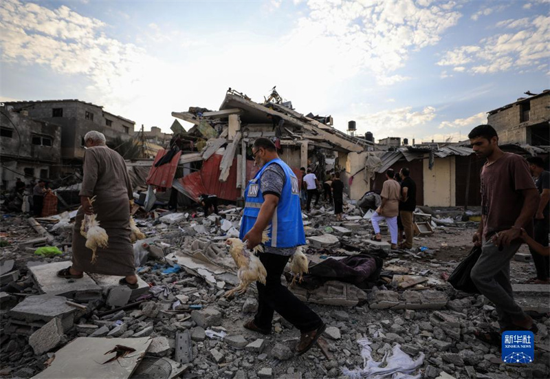 10月27日，在加沙地帶南部城市汗尤尼斯，人們經(jīng)過以軍襲擊后的房屋廢墟。