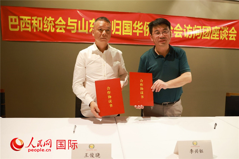 中國僑聯(lián)副主席、山東省僑聯(lián)主席李興鈺（右）與巴西和統(tǒng)會會長王俊曉簽署合作協(xié)議書。人民網(wǎng)記者 陳海琪攝