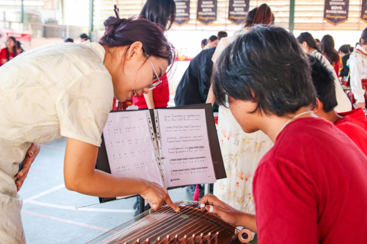 志愿者教師指導(dǎo)學(xué)生彈奏古箏?；顒又鬓k方供圖