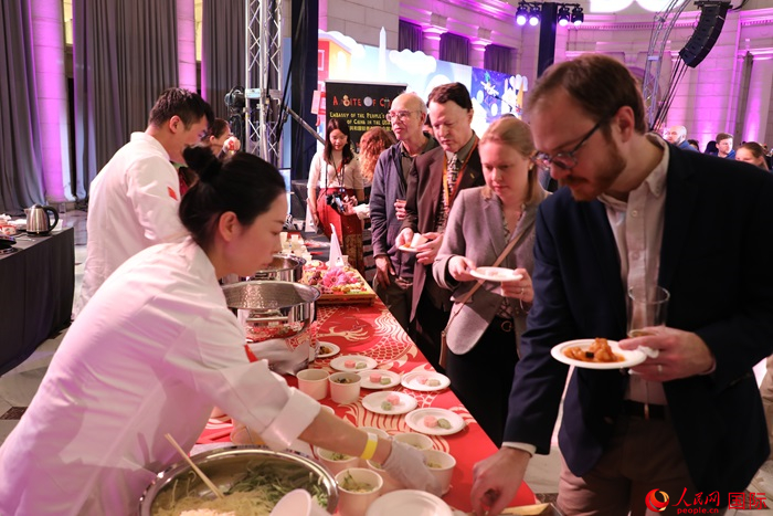 當?shù)貢r間3月7日晚，華盛頓聯(lián)合車站廣場舉行駐美使團“使館主廚挑戰(zhàn)賽”。圖為當?shù)孛癖娫谥袊古_前體驗中國美食。人民網(wǎng)記者 李志偉攝