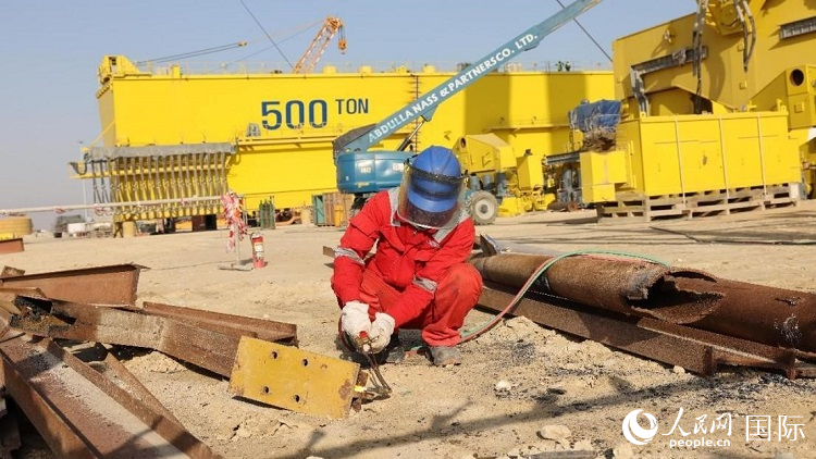 工人正在龍門吊吊裝現(xiàn)場切割金屬件。人民網記者管克江攝