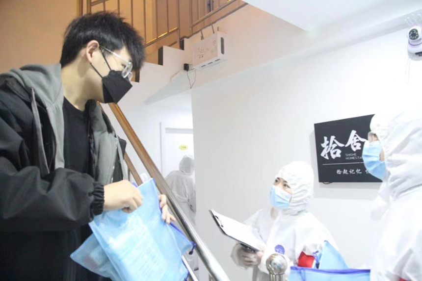 社區(qū)工作人員和志愿者身穿防護(hù)服上門送馬應(yīng)龍大健康防疫包。徐帥攝