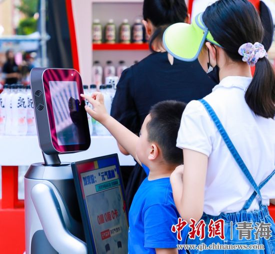 圖為一名小朋友正在和機器人“志愿者”進行互動。 沐聞 攝