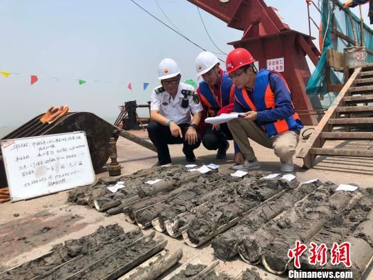 圖為勘察設(shè)計人員與海事局工作人員查看巖芯情況?！∥赫?攝