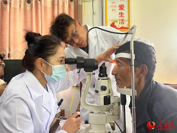 王紅英（左）和團(tuán)隊(duì)成員為達(dá)熱村村民檢查眼睛。人民網(wǎng)記者 杜燕飛攝