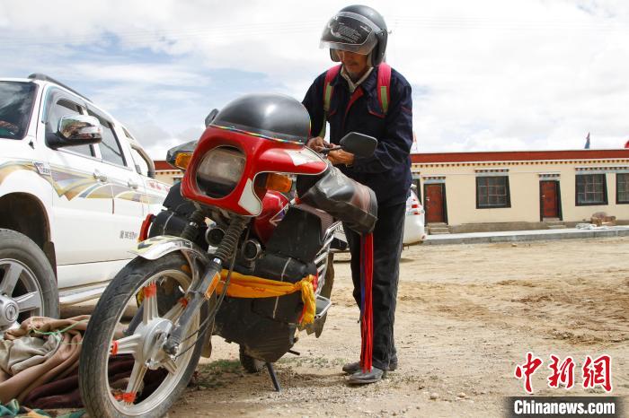 圖為白瑪準(zhǔn)備騎摩托車巡湖?！≮w朗 攝