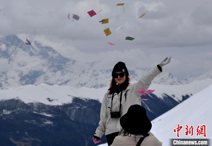 圖為5月14日，游客在西藏林芝色季拉山觀景臺(tái)拋灑“隆達(dá)”(風(fēng)馬旗，藏族民眾的一種祈福方式)?！±盍?攝