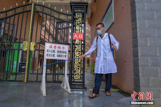 資料圖：海口經(jīng)濟學院的工作人員在學生宿舍樓入口消毒。 中新社記者 駱云飛 攝