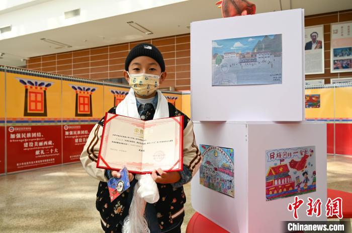圖為一名獲獎(jiǎng)學(xué)生與自己的繪畫作品合影?！≮w朗 攝