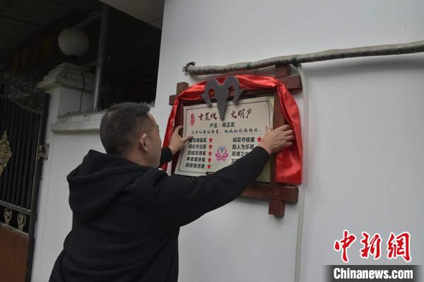 桂溪鎮(zhèn)渭溝村政府工作人員為“十星級文明戶”掛上牌匾?！钣?攝