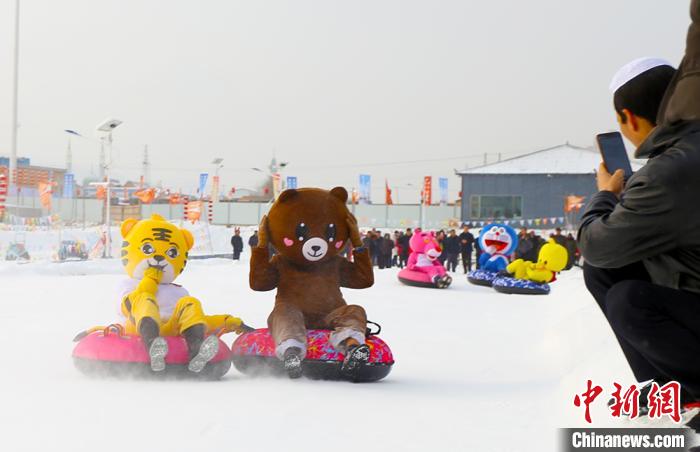 圖為臨夏市南龍鎮(zhèn)馬家莊村舉辦的鄉(xiāng)村文化旅游節(jié)上，游客穿著卡通服裝在體驗雪上飛碟項目。近年來，臨夏州形成了“春賞花、夏避暑、秋摘果、冬玩雪”的全季節(jié)旅游產(chǎn)品體系。(資料圖) 高展 攝