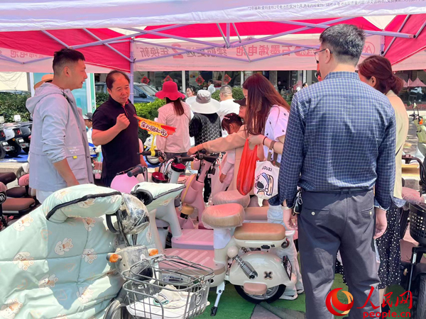 某電動自行車品牌工作人員向消費者介紹以舊換新相關(guān)情況。人民網(wǎng)記者 杜燕飛攝