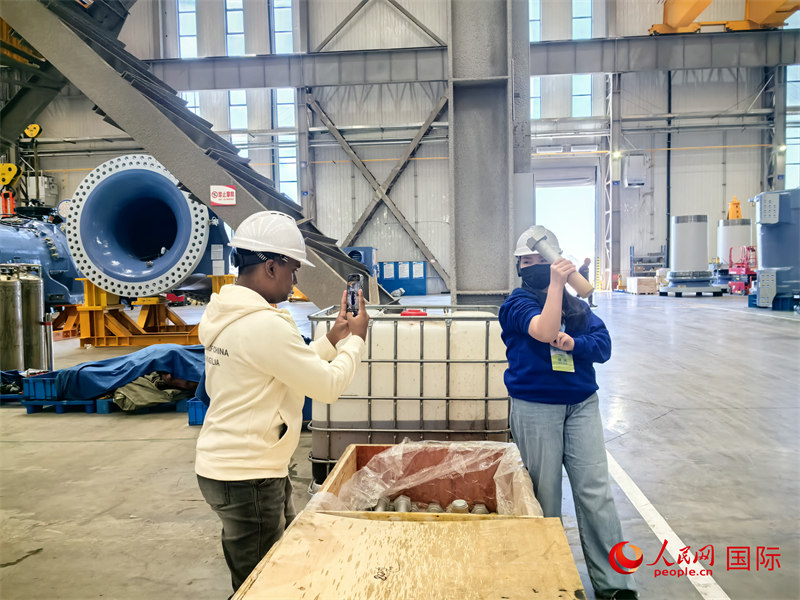 外媒記者掂量廠房?jī)?nèi)的巨型螺栓。人民網(wǎng) 楊春燕攝