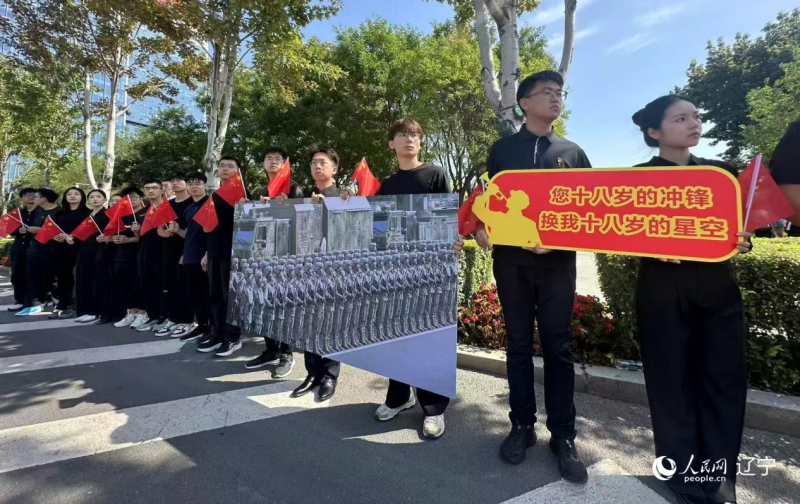 沈陽市人民廣場上，大學(xué)生們手持閱兵的圖片，告慰英烈。人民網(wǎng)記者 周頌雪攝