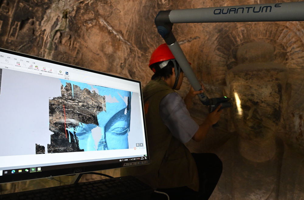 2025年4月9日，武漢大學(xué)文化遺產(chǎn)智能計(jì)算實(shí)驗(yàn)室團(tuán)隊(duì)成員在魏字洞使用關(guān)節(jié)臂掃描儀對(duì)佛像進(jìn)行數(shù)字化掃描。圖片來源新華社