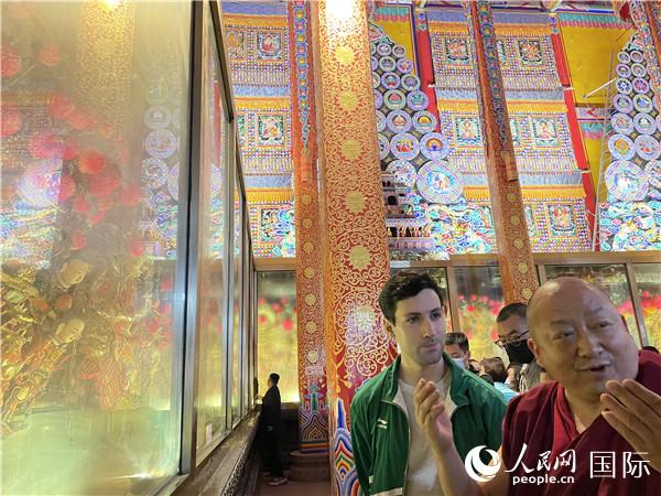 7月25日，省級(jí)非物質(zhì)文化遺產(chǎn)項(xiàng)目塔爾寺酥油花的代表性傳承人朋措堅(jiān)參（右）在塔爾寺酥油花館講解酥油花的制作過程。人民網(wǎng) 謝瑩攝