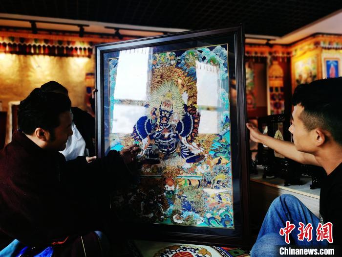 圖為久美尖措(左)與徒弟們展示唐卡作品。　張?zhí)砀?攝