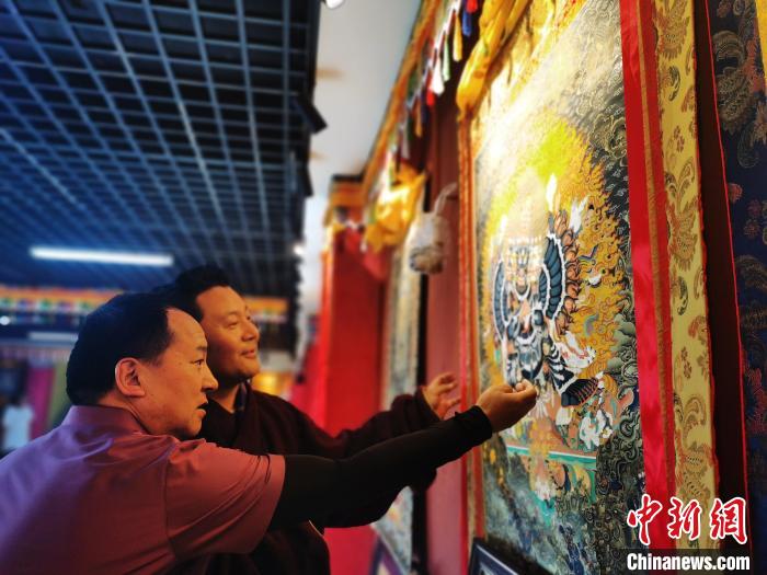 圖為久美尖措展示唐卡作品?！?zhí)砀?攝