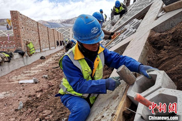 圖為光伏發(fā)電項目施工區(qū)工人在護坡鋪設空心磚?！±铍h 攝