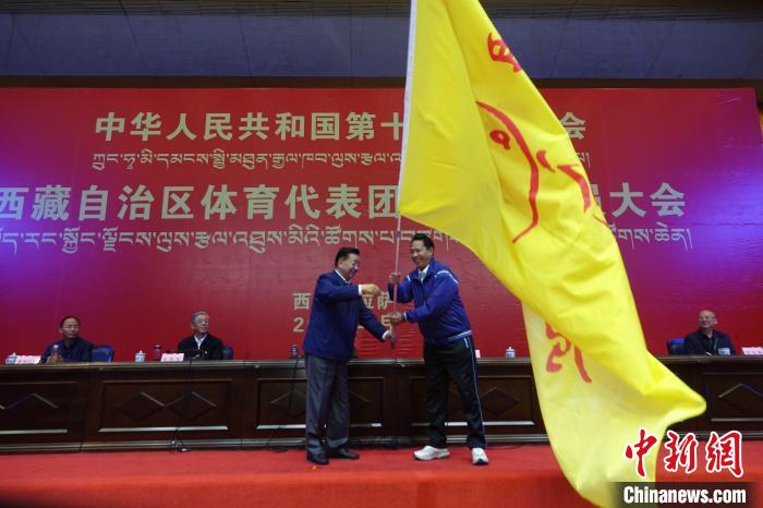 西藏自治區(qū)副主席甲熱·洛桑丹增授代表團(tuán)團(tuán)旗，西藏自治區(qū)體育局局長尼瑪次仁接旗?！∪轿木?攝