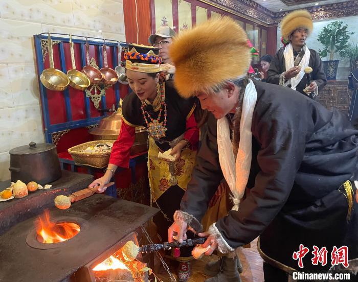 圖為人們在火上烤節(jié)日美食“結(jié)達”?！∪轿木?攝