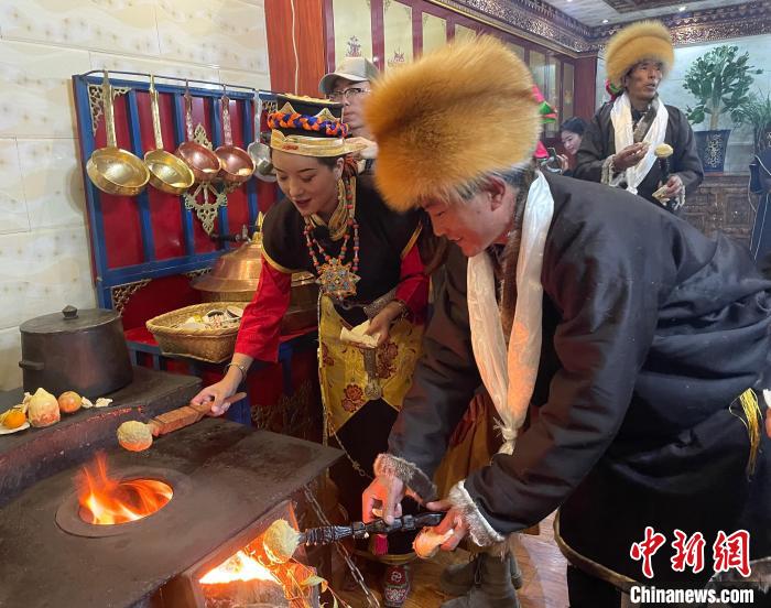 圖為人們在火上烤節(jié)日美食“結(jié)達(dá)”?！∪轿木?攝