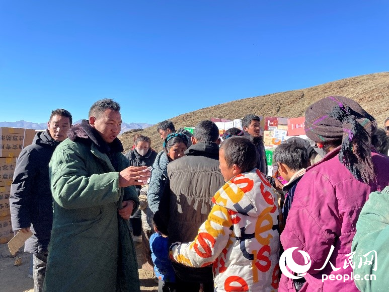 定日縣公安局干警頓珠次仁（左二）正在協(xié)助分發(fā)物資。人民網(wǎng)記者 郝潔攝